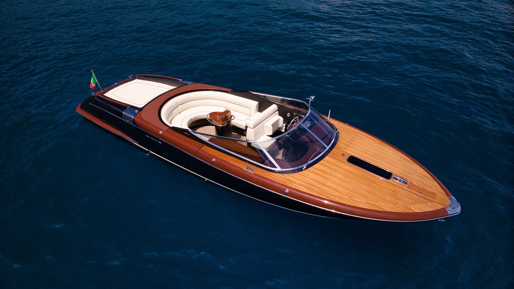 Classic Riva runabout with mahogany and teak deck on deep blue Mediterranean water — Italian yacht craftsmanship and heritage